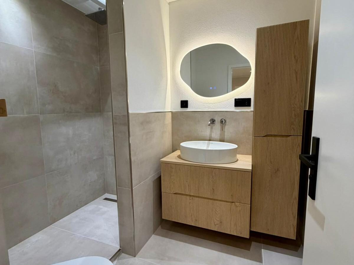 Saniertes Badezimmer mit bodengleicher Dusche und Waschtisch in Holzoptik in Kaiserslautern
